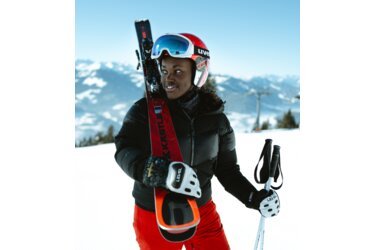 Skier holding skis and poles in the snow.