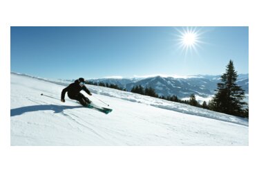 Skieur sur une pente enneigée sous un ciel bleu.
