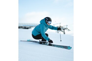 Skieuse dévalant une pente enneigée.
