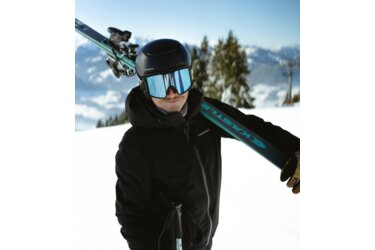 Skieur avec des skis et un casque sur l'épaule.