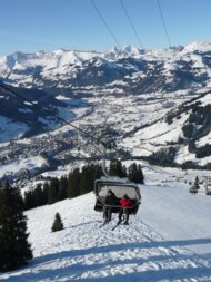 Chairlift with two people in front of a snowy mountain landscape | © Information Gstaad Saanenland Tourismus 
