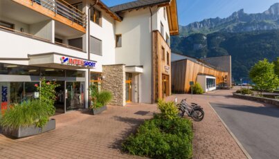 Magasin Intersport avec des vélos garés devant et des montagnes en arrière-plan