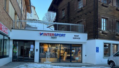 Facade of an INTERSPORT Rent shop in a snowy village center.