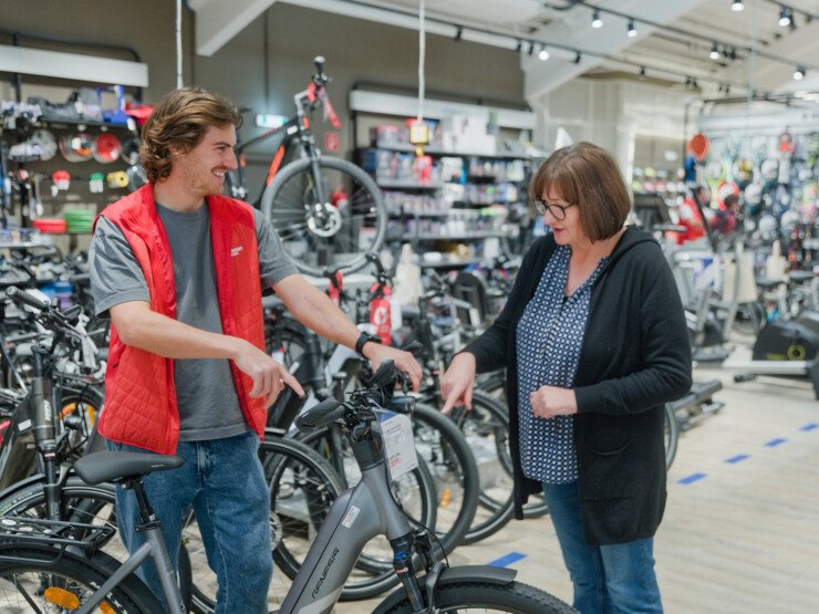 Mitarbeiter zeigt einer Dame ein E-Bike